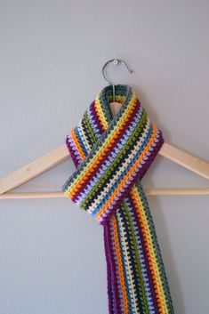 a multicolored crocheted scarf hanging on a clothes hanger