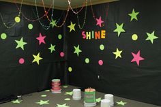 a room with green and pink stars on the wall, tinsels hanging from the ceiling