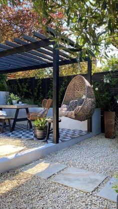 an outdoor dining area with chairs and tables under a pergolated roof, surrounded by gravel