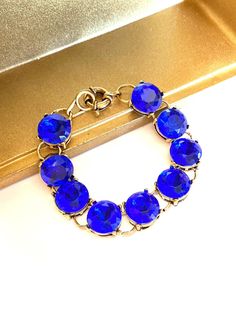 This sparkly round stone sapphire blue bracelet features eye-catching sparkling stones set within an antique gold-tone setting.   Bracelet is 7-3/4" long (from end of clasp to end of hook) and each rhinestone is approximately 1/2" wide. Not intended for children ages 13 and under. Nickel-free Sapphire Jewelry For Party, Sapphire Nickel-free Jewelry For Party, Jeweled Round Crystal Bracelet As Gift, Jeweled Round Crystal Bracelet For Gift, Blue Jeweled Bracelets As Gift, Jeweled Bracelets For Formal Occasions, Jeweled Crystal Bracelet Gift, Vintage Round Crystal Bracelet For Gift, Blue Rhinestone Round Jewelry