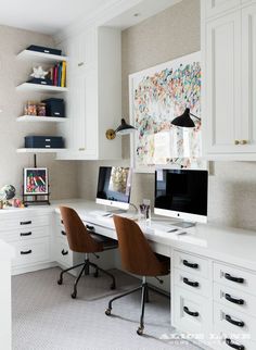 a white desk with two computers on it in a room filled with books and other items