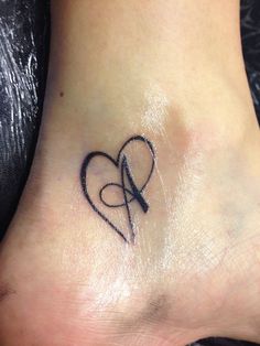 a small tattoo on the foot of a woman's foot with an arrow in the shape of a heart