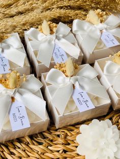 four boxes with white bows are sitting on a wicker basket next to some flowers