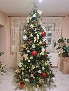 a decorated christmas tree in the corner of a living room with white tile flooring