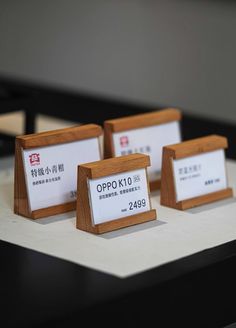 three small wooden plaques sitting on top of a white table next to another sign that says opokuto