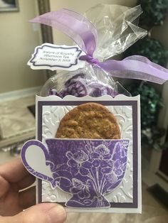 a person holding up a card with a cookie in the cup on it's side