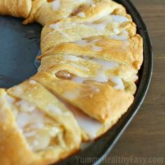 a pastry with icing sitting in a pan next to a glass of milk on a table