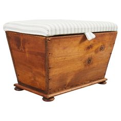 an old wooden box with a white cushion on it's lid and legs that are attached to the sides