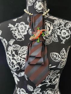 This  Chocolate Brown Striped Necktie Necklace is made with a (Barry Wang) woven silk tie, and features a Multi-Color Rhinestone Brooch strung on your choice of an adjustable Rosary Chain Ribbon Tie Pearl Necklace or an adjustable Elastic Band. The soft, comfortable fabric sits perfectly on any size chest, while the adjustable necklace feature allows you to customize the fit to your liking. Measuring at a versatile length, this necktie necklace is designed to be a one-size-fits-all. View all Wom Necktie Necklace Diy, Elegant Multicolor Brooches For Formal Occasions, Elegant Brown Formal Brooches, Women Neck Tie, Necktie Necklace, Tie Brooch, Tie Crafts, Tie Necklace, Jewelry Brooch