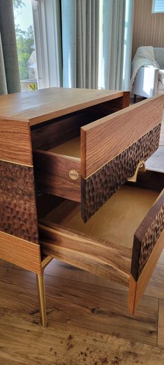 a wooden desk with drawers on it in front of a window and wood flooring