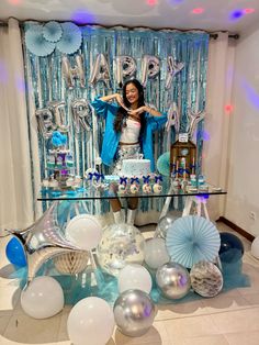 a woman standing in front of a cake surrounded by balloons