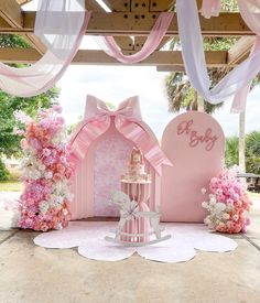 a pink and white cake is on display in front of a backdrop for a baby's first birthday