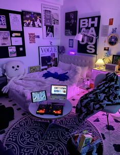 a bedroom with two laptops and a bed in the corner, all lit up by purple lighting