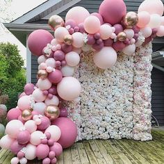 a bunch of balloons that are on top of a wooden floor in front of a house