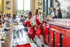 people in red aprons are standing at the bar