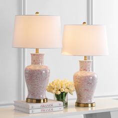 two pink and white vases sitting on top of a table next to a lamp