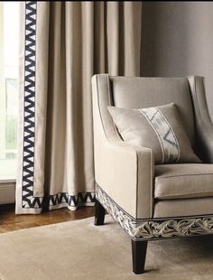 a chair sitting in front of a window next to a rug