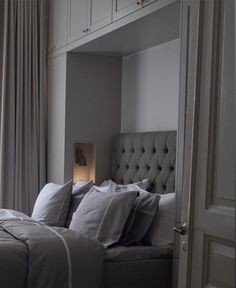 a bed with white sheets and pillows in a room