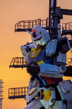 the giant robot is standing in front of an orange and yellow sky with stairs leading up to it