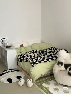 a cat sitting on top of a bed in a room with two chairs and a rug