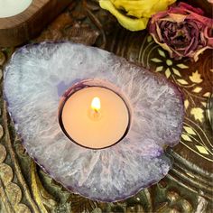 a lit candle sitting on top of a piece of wood