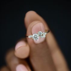 a woman's hand holding an engagement ring with three diamonds on it and the middle finger