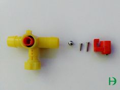 two yellow and red plastic parts on a white surface next to screws, nuts and washers