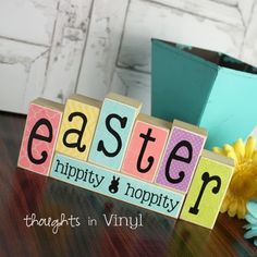 the word easter spelled with blocks on a table next to flowers and a potted plant