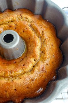 a bundt cake in a metal pan on a cooling rack with oil coming from the top