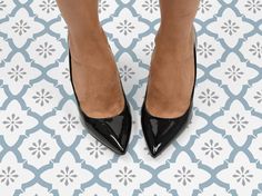 a woman's legs in black high heels on a blue and white tile floor