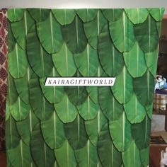 a green wall with large leaves on it and a sign that says karragifworld