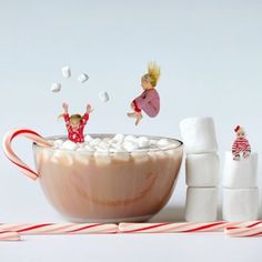 marshmallows are falling into a bowl of hot chocolate and marshmallows