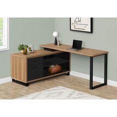 a computer desk with a laptop on top of it next to a rug and window