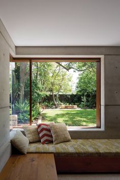 a couch sitting in front of a large window next to a wooden table and bench