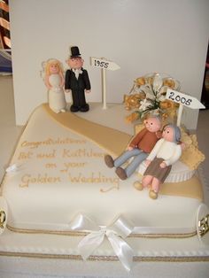 a wedding cake is decorated with figurines on top and an anniversary sign in the middle