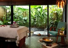 a spa room with a bed, bathtub and plants in the window sill