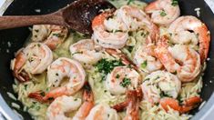 shrimp and grits cooking in a skillet with a wooden spoon on the side