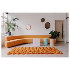 an orange couch sitting on top of a white floor next to a potted plant