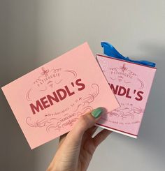 two pink cards with the words mendl's on them are being held up