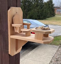 a wooden object on the side of a building with a car in the back ground