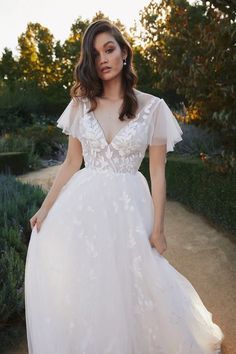 a woman in a white dress standing on a path