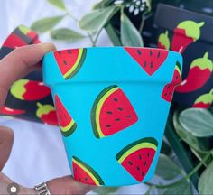 a hand holding a cup with watermelon designs on it