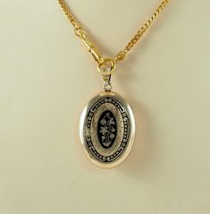 A charming antique Victorian oval gold filled and black enamel sentimental or mourning locket back pendant, in a yellow gold tone. The front with a bleeding heart flower in full bloom with two further buds and foliage, in gilt on a black ground, with a border of scrolls and tiny flower heads.  With an opening machine engraved panel to the reverse with space within for hair or a keepsake, with both frames and one glass. Unmarked. The chain is for display only. Germany 1880s.  8g The opening panel Victorian Black Enamel Pendant Jewelry, Victorian Etched Locket Necklace For Memorial, Victorian Engraved Locket Necklace For Memorials, Vintage Gold Locket Necklace With Oval Link, Vintage Gold Oval Link Locket Necklace, Antique Gold Necklaces With Black Enamel, Antique Black Locket Jewelry, Vintage Black Locket Jewelry, Collectible Black Etched Jewelry