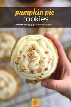 a hand holding a frosted cupcake with walnuts on top