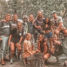 a group of young people posing for a photo on a wooden deck with trees in the background