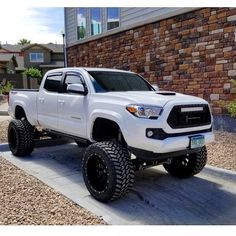 a white toyota truck parked in front of a brick building with black wheels and tires