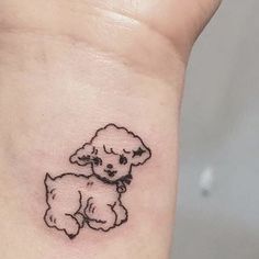 a small black and white dog tattoo on the left wrist, it looks like a little poodle