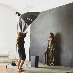 a woman is taking a photo in front of a black backdrop with a gold dress