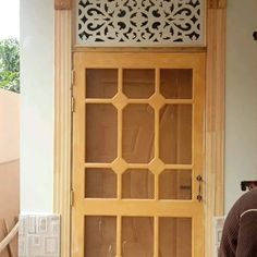 a man standing in front of a wooden door with glass panels on the top and bottom