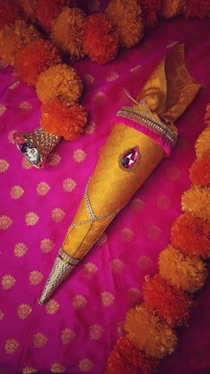 two decorative items on a pink and orange cloth with pom poms around them